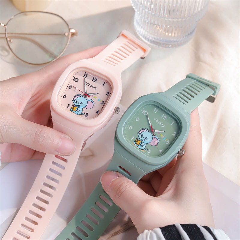 Two pastel-colored children’s luminous digital watches in white with square faces and cartoon elephant designs on the dials.