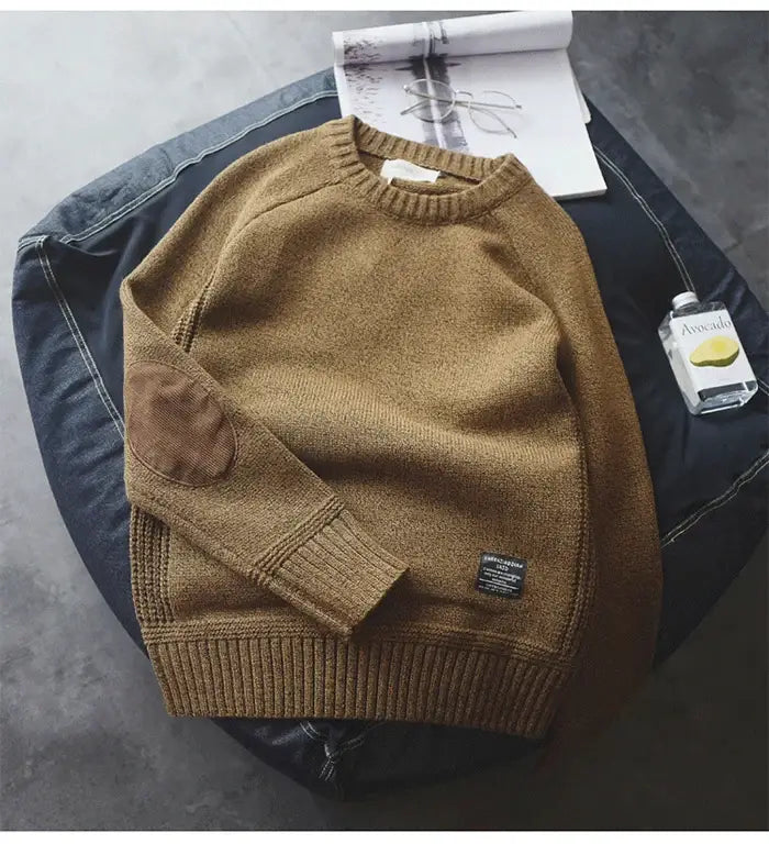 Un pull en laine pour homme couleur moutarde, surdimensionné, en maille décontractée, avec poignets et bas côtelés, comportant un patch sur la manche gauche.