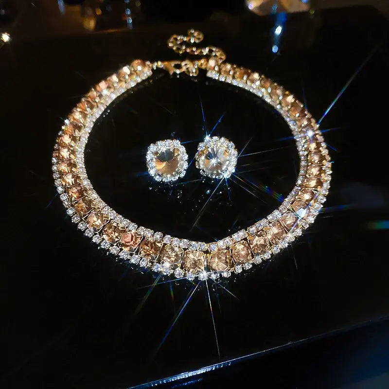 A glamorous crystal necklace and earring set with a bold two-tone design featuring alternating champagne-colored and clear crystals embedded in gold-toned metal, ideal for pink ab wedding jewelry.