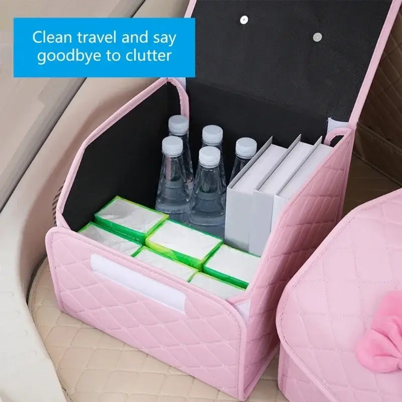 Pink quilted fabric car trunk organizer with bow and black interior holding water bottles and green-wrapped items.
