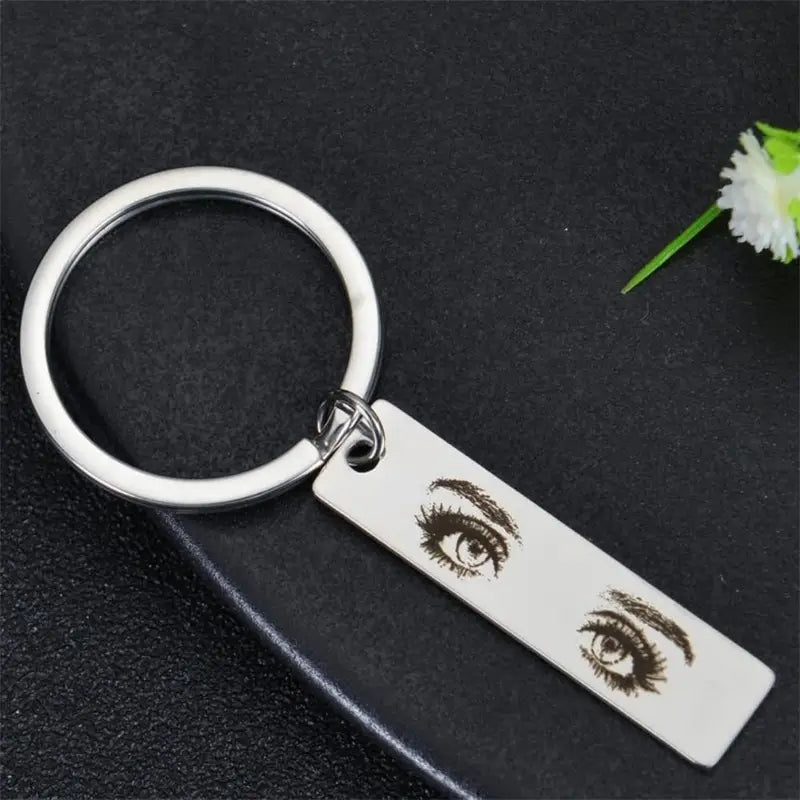 Silver stainless steel keychain with a rectangular tag featuring an engraved pair of detailed brown expressive eyes for a custom eye photo engraved keychain.