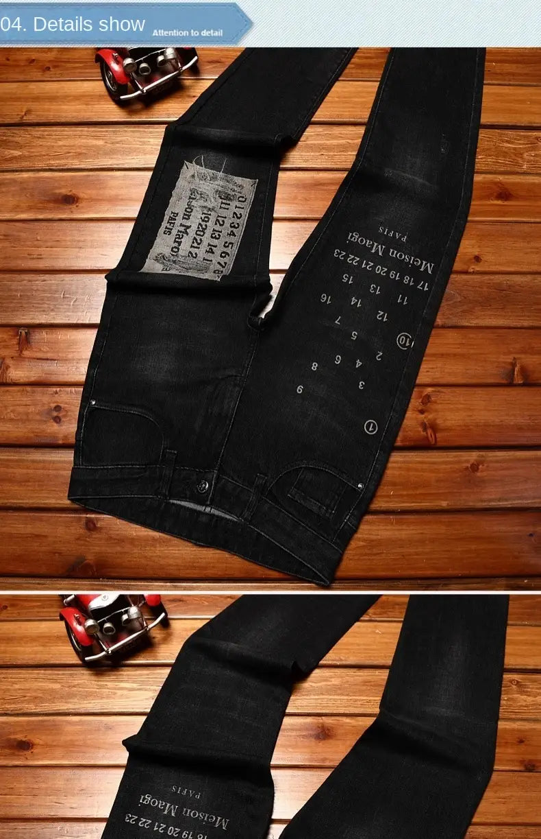 Mens slim fit printed black denim jeans featuring distressed design with white printed text and numbers along the leg and a faded patch on the back pocket shown from the back side.