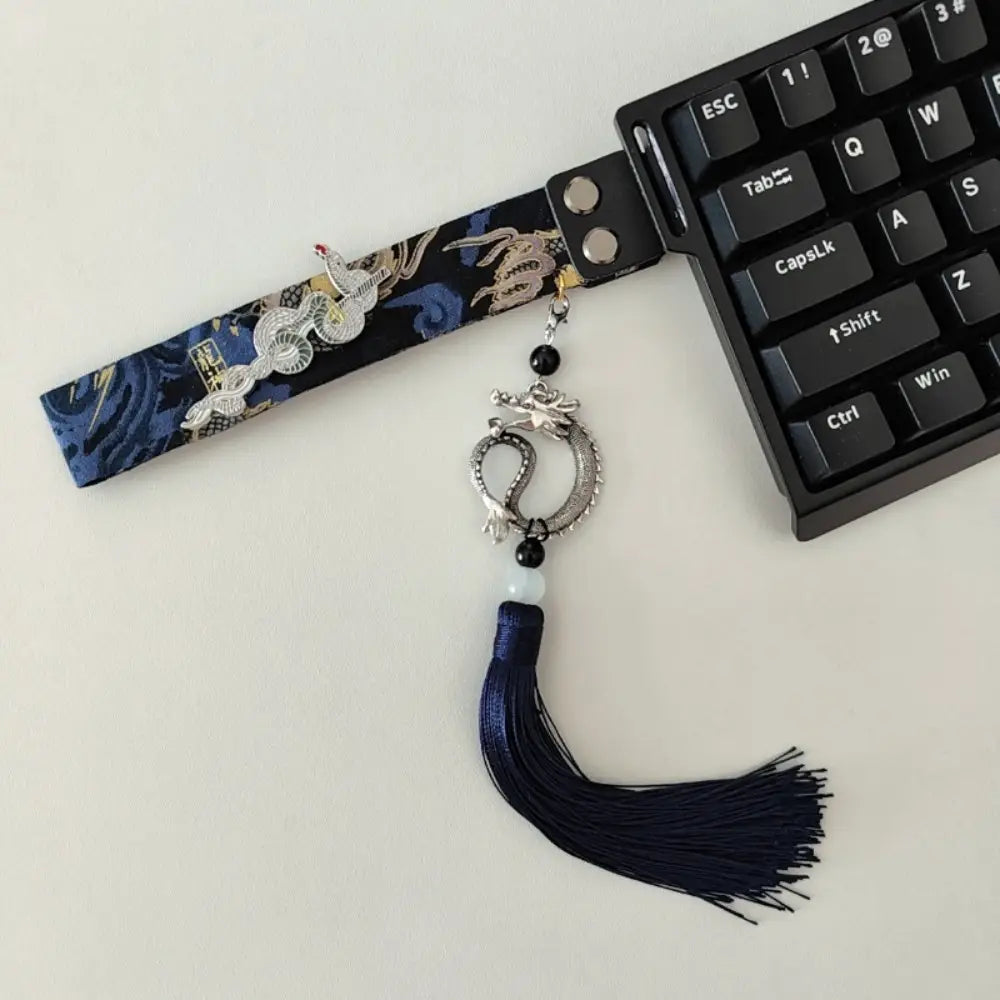Sangle de poignet brodée bleu marine sur le thème d’un dragon et d’une grue, avec une breloque de dragon aux tons argentés et un pompon assorti pour la sangle personnalisée du modèle Ribbon Dragon du clavier Wooting.