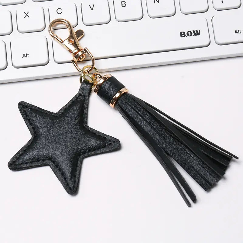 Black star-shaped leather keychain for women with a gold-tone metal clasp and matching tassel.