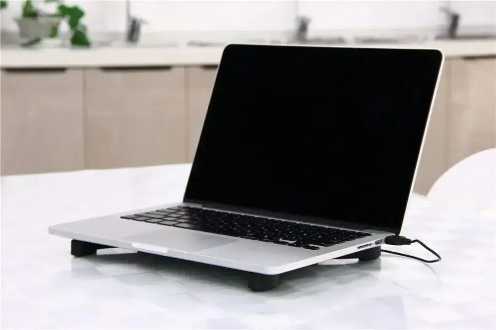 silver macbook air laptop with black keyboard and screen resting on a black dual fan usb powered laptop cooling pad designed for laptop cooling.