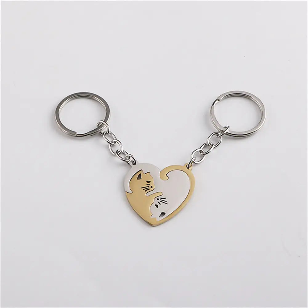 Two interlocking heart-shaped cat couple keychains in contrasting gold and silver tones made of metal.