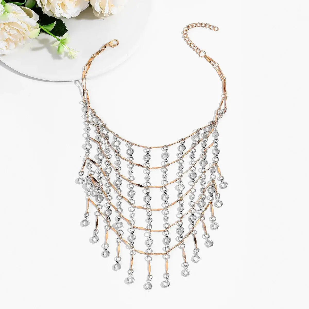 Collier ras du cou à gland en cristal, doté de chaînes métalliques à plusieurs niveaux en or rose et ton argent, ornées de perles en cristal pendantes.