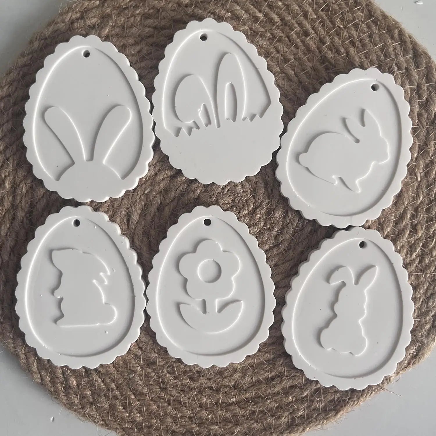 white ceramic easter egg-shaped ornaments with embossed bunny flower and silhouette designs created using the easter bunny silicone resin pendant mold