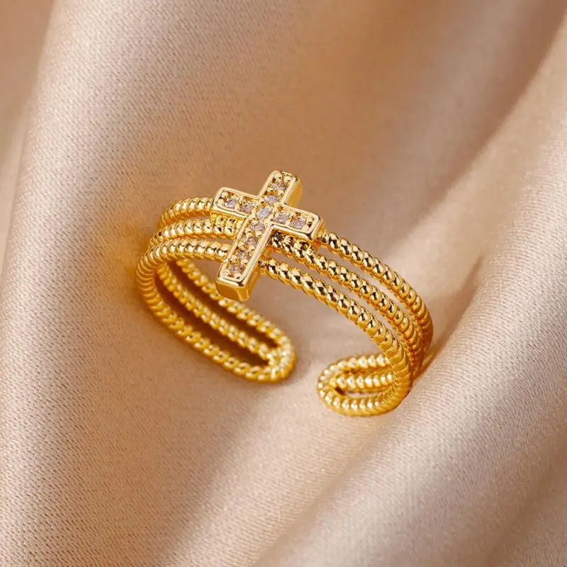 Anillo ajustable de acero inoxidable color dorado para mujeres, con una banda texturizada tipo cuerda y un motivo central en forma de cruz, con piedras de circonia cúbica transparentes, estilo joyería de boda vintage.