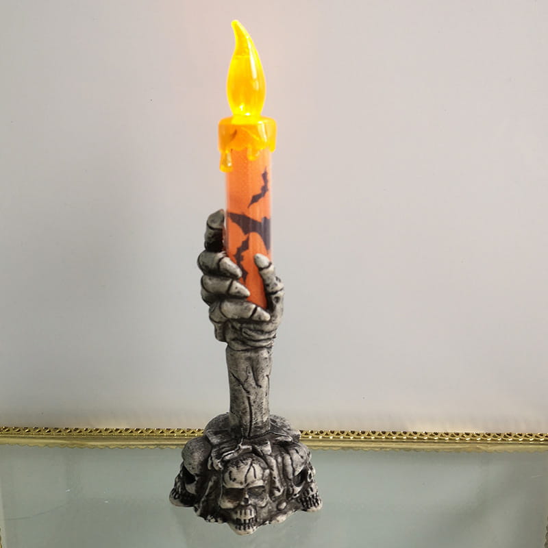 Skeleton hand led candle with an orange body featuring black bat silhouettes held by a gray skeletal hand and mounted on a skull base perfect for party happy halloween and happy halloween party decorations.