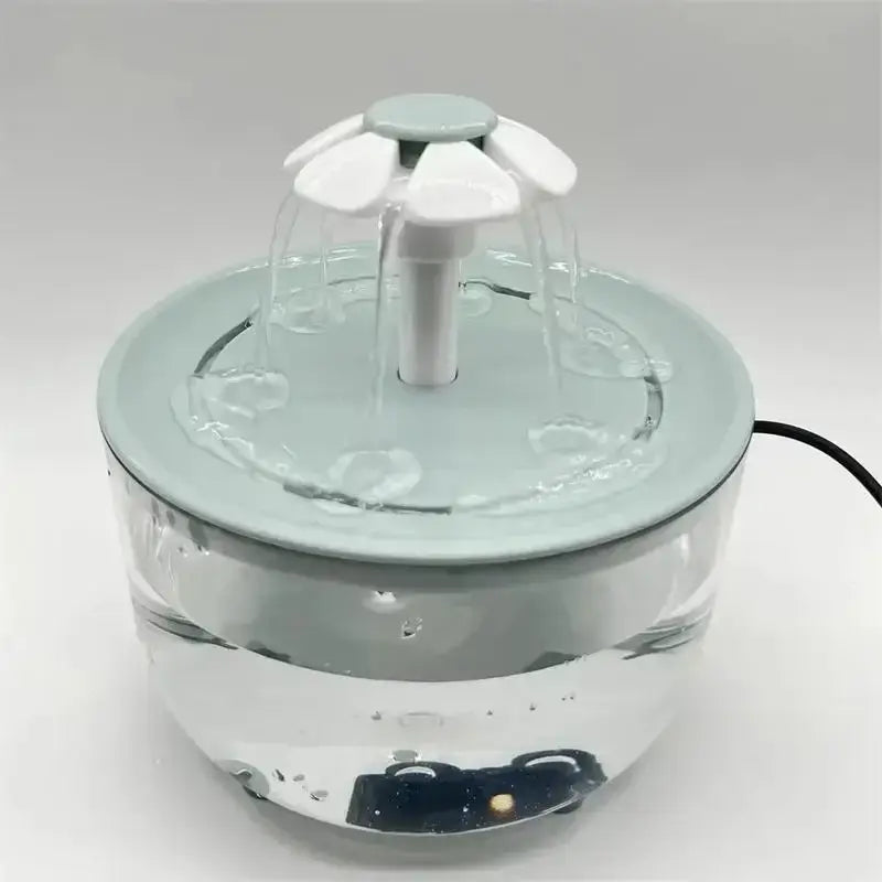 ein eleganter hellblauer automatischer Trinkwasserspender für Haustiere mit transparentem Wassertank und einem blumenförmigen Auslauf, von vorne dargestellt.