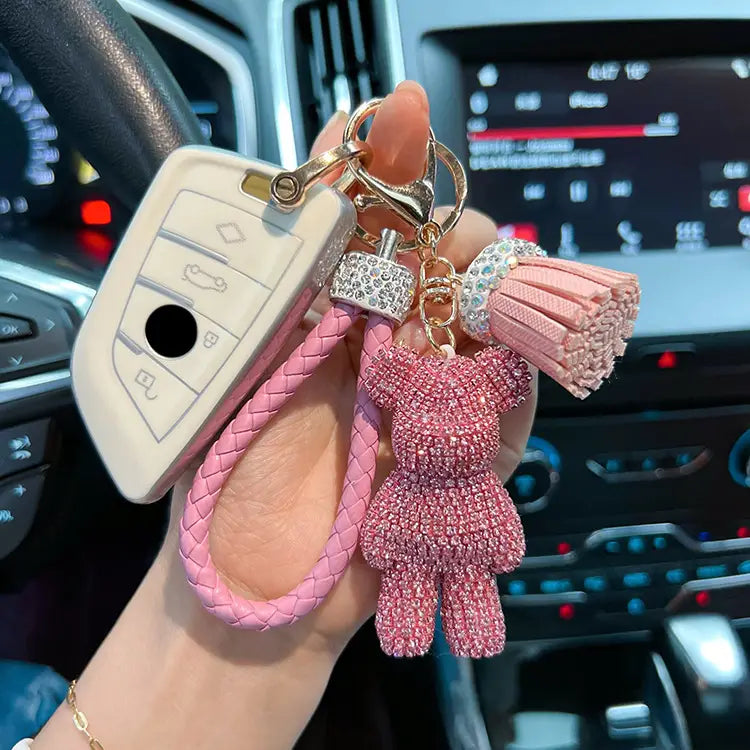 Pink rhinestone-encrusted bear keychain with braided pink leather strap and tassel.