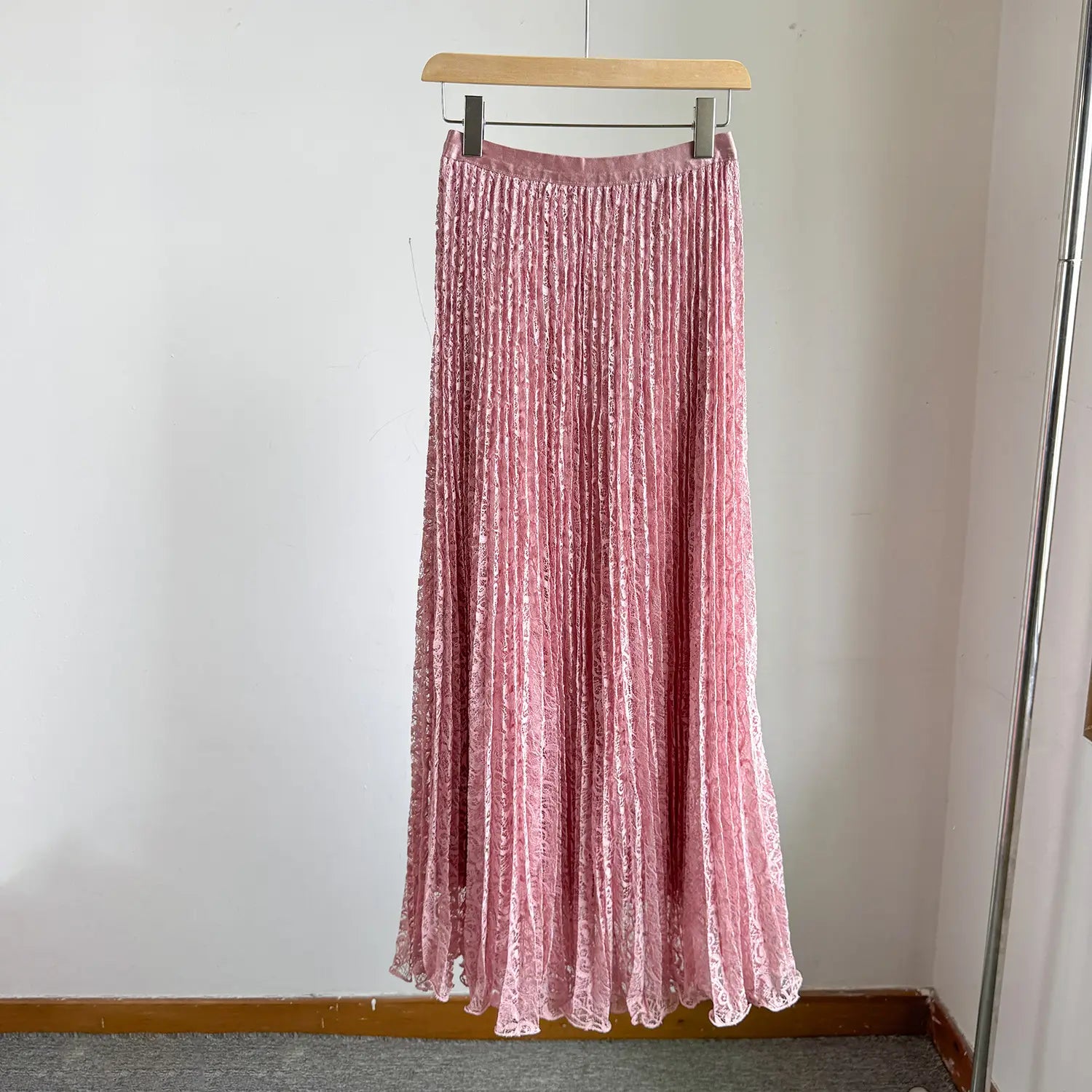 A pink high waist pleated midi skirt made of velvet with lace trim at the hem suitable for Y2K streetwear.