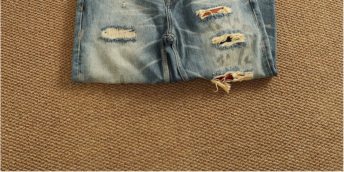 Distressed patchwork denim jeans for men in blue with frayed, ripped details and a faded wash.