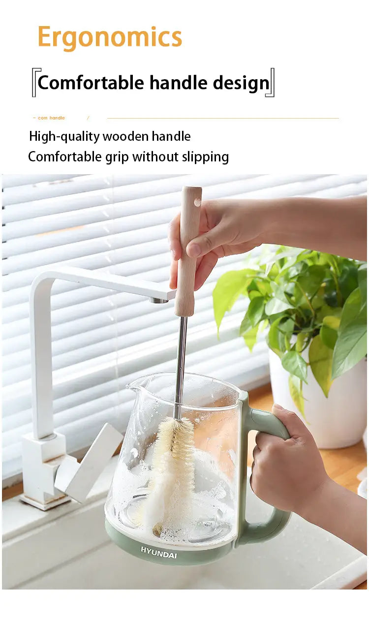 Une carafe en verre transparente élégante avec un manche et une base vert sauge, portant le logo Hyundai à côté d’une brosse à bouteille en bois à long manche pour le nettoyage approfondi.