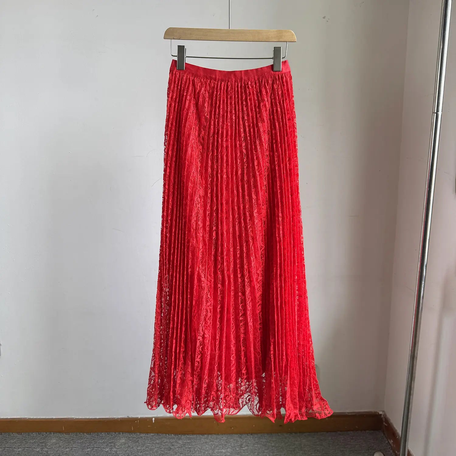 A vibrant red high waist pleated lace midi skirt hanging on a wooden hanger designed for Y2k streetwear.