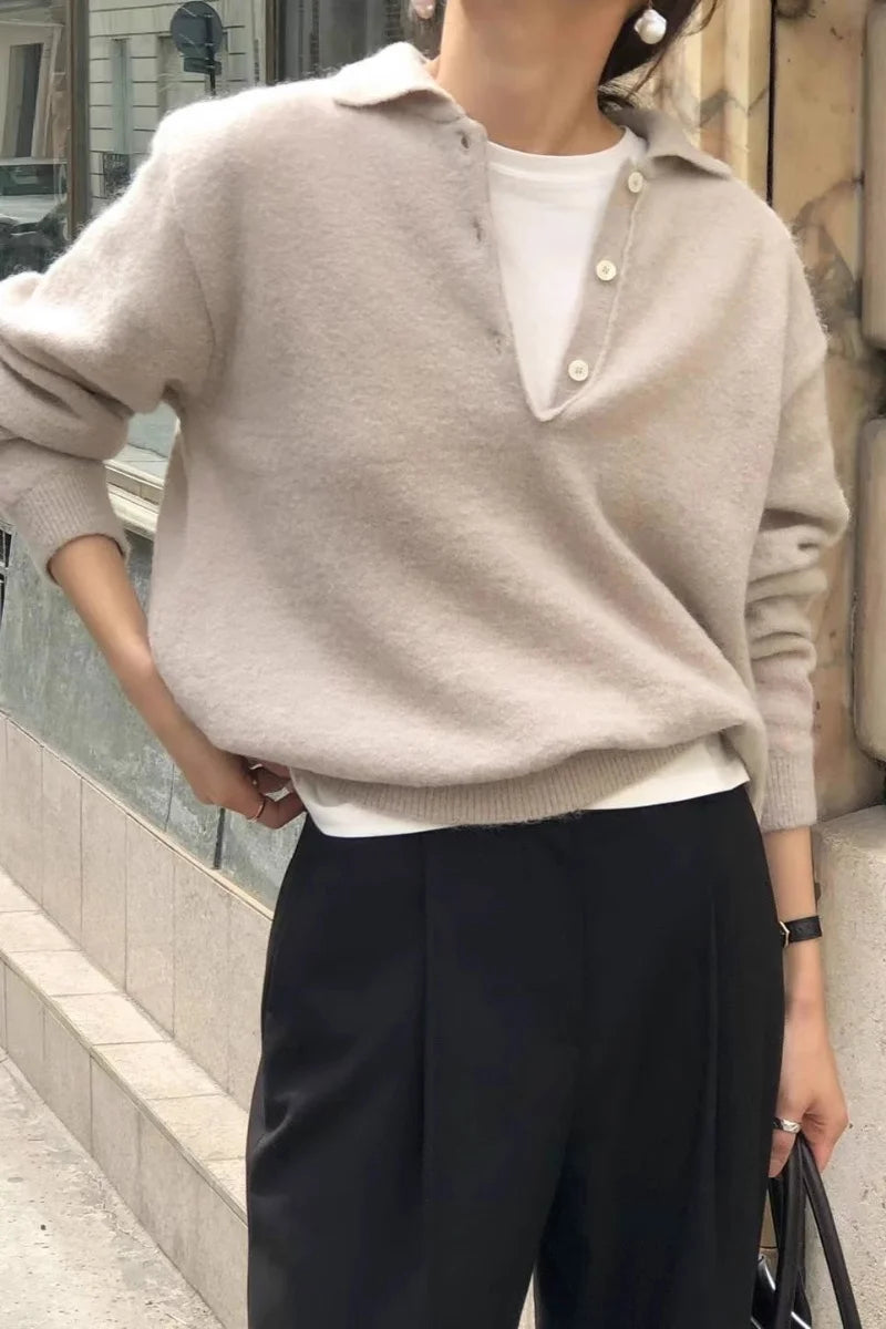 Un pull pour femmes en laine mérinos beige à encolure en V, présentant un modèle type polo en maille avec patte boutonnée et poignets côtelés.