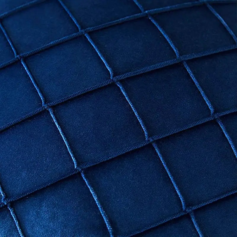 tissu matelassé bleu marine profond avec motif quadrillé texturé sur la face arrière d’une housse de coussin en velours gris avec pompons, conçu pour des housses de coussin recevant des retours positifs.