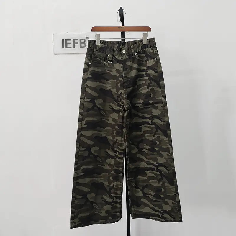 Iefb camouflage wide leg denim jeans in green and black camouflage pattern hanging on a wooden hanger.