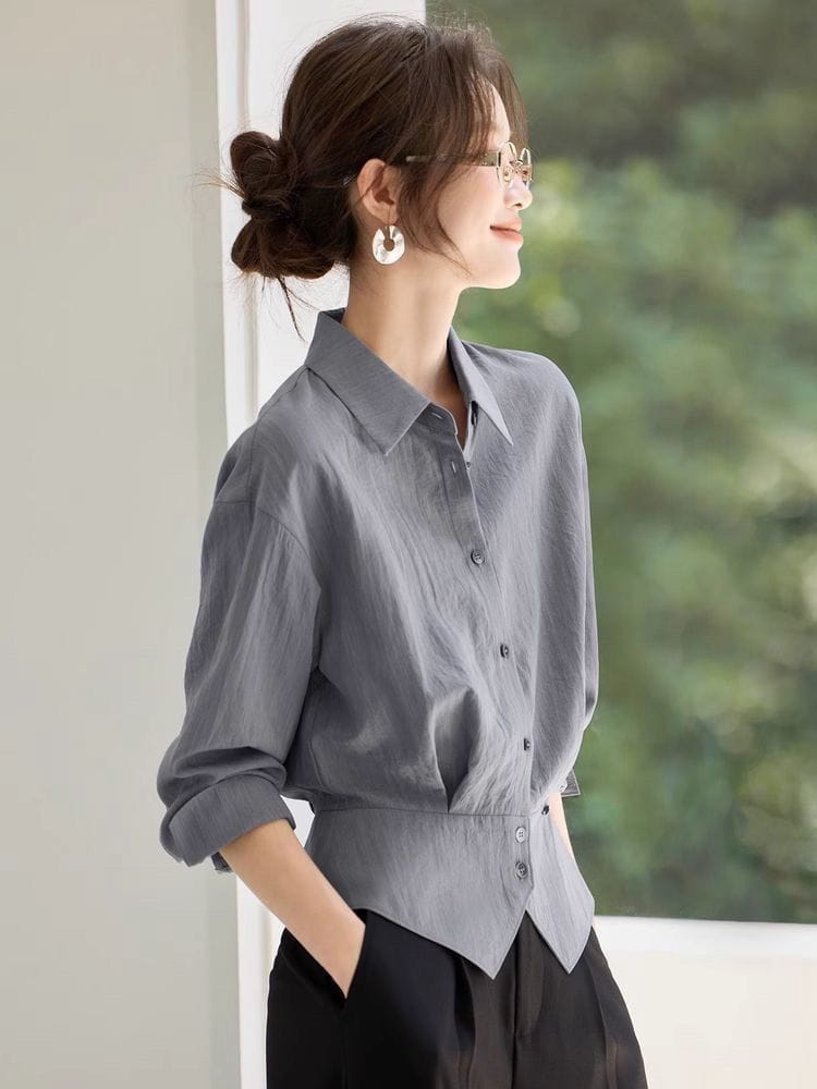 Blouse chemise manches longues grise à coupe ajustée et plis de taille subtils, conçue pour une tenue de bureau.