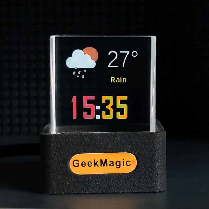 A sleek black rectangular digital display with a silver frame showing weather and time on the screen in the Geekmagic Smart Weather Station Crystal Gif Clock.
