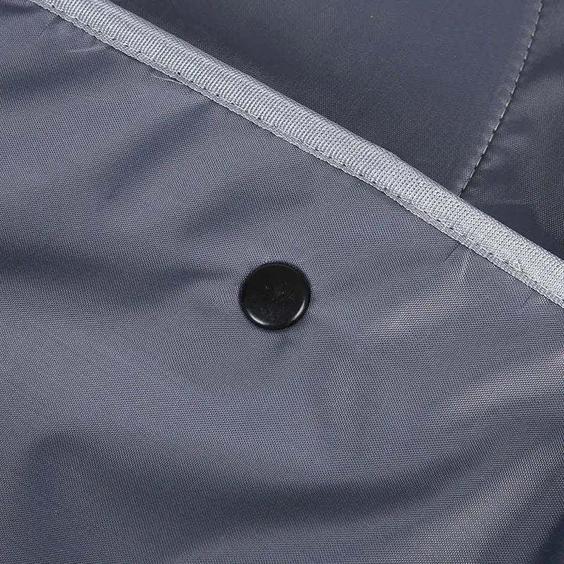 Sac à dos de transport pour animaux en nylon gris foncé, avec bouton noir et surpiqûres argentées le long de la couture, conçu comme sac à dos de transport pour les petits chats et les petits chiens.