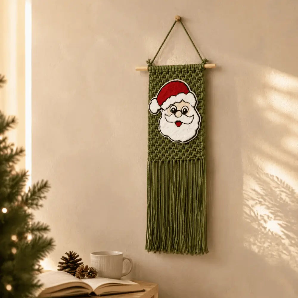 Green macrame Christmas wall hanging tapestry featuring an embroidered Santa Claus face with a red hat and white beard.