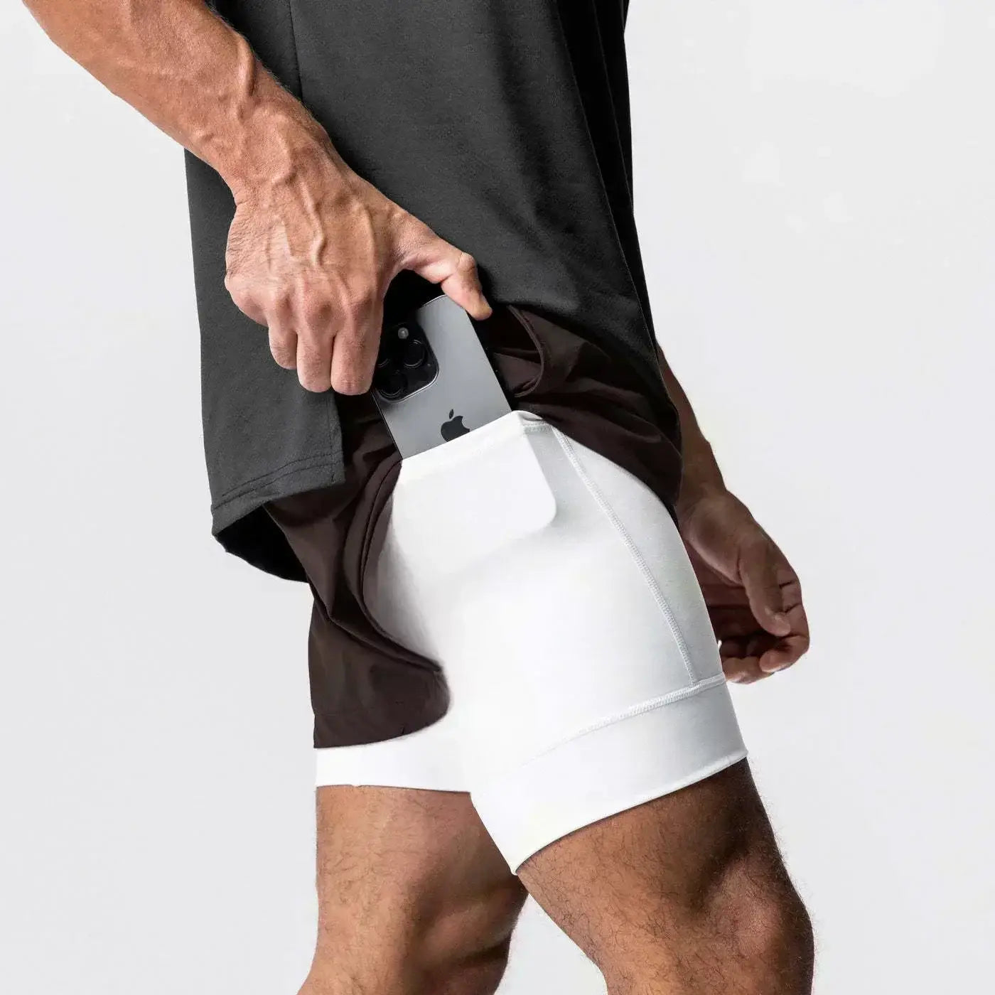 Hombres, pantalones cortos atléticos 2 en 1 para gimnasio blancos con bolsillo integrado para un teléfono inteligente y trabilla para la toalla que ofrece soporte durante los entrenamientos.