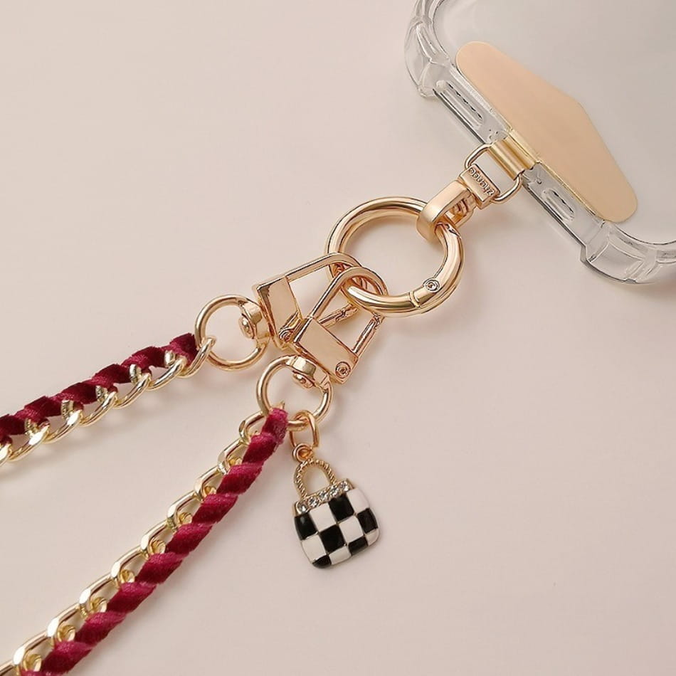 Handy-Handgelenkriemen aus goldfarbener Kette als Anti-Lost-Handylanyard mit einer goldfarbenen Kette, bordeauxrotem geflochtenem Kord und einem schwarz-weißen karierten Handtaschen-Anhänger.