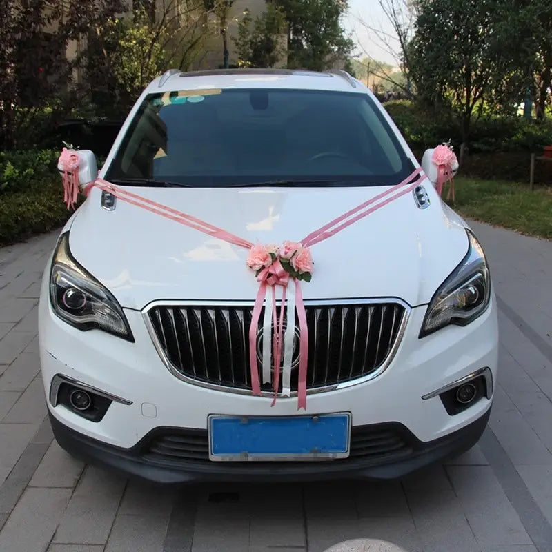 SUV Buick blanc décoré de rubans roses et de décorations florales artificielles provenant de l’ensemble de décoration florale artificielle pour voiture de mariage destiné aux occasions particulières.