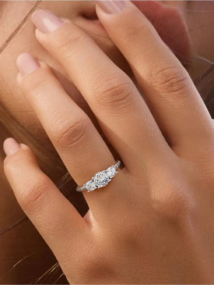 A delicate sterling silver zircon ring for women featuring a three-stone design with a central round diamond and two smaller diamonds set on an elegant band with fine detailing.
