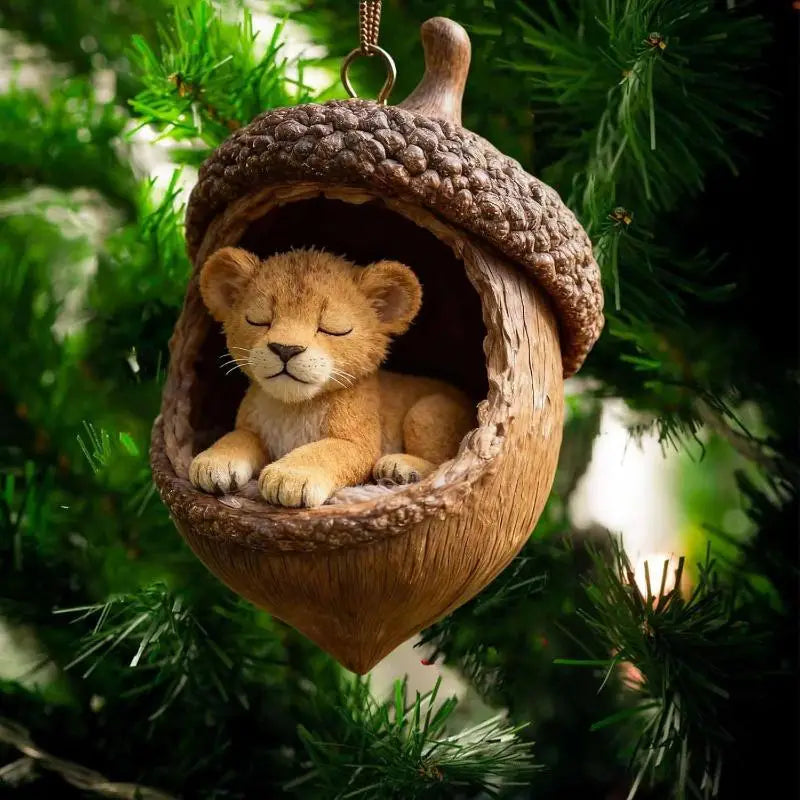 眠っているライオンの子どもが中に収まった、魅力的などんぐり形の動物クリスマスオーナメント。クリスマスツリーの装飾用のために、詳細なアクリルの質感で仕上げられています。