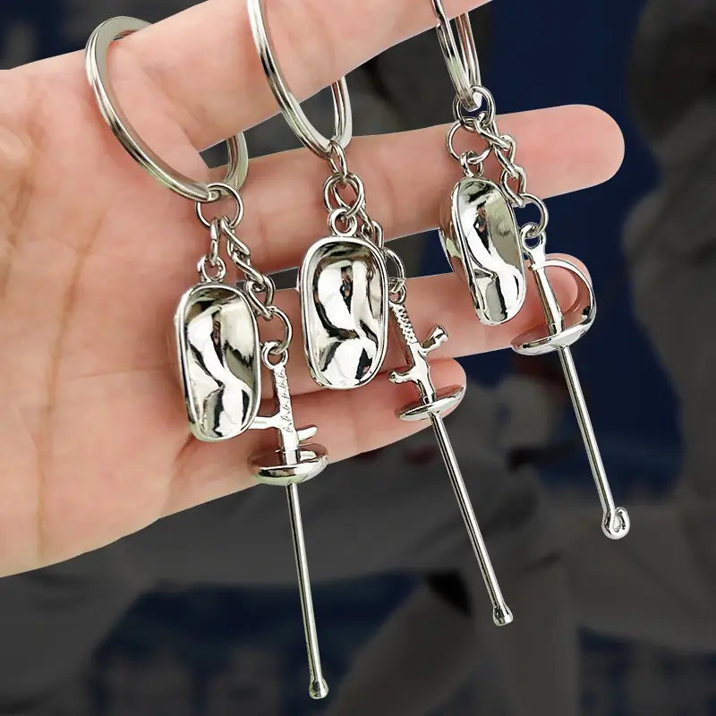 Silver metallic fencing keychains feature detailed sword and glove designs as metal sports sword jewelry.