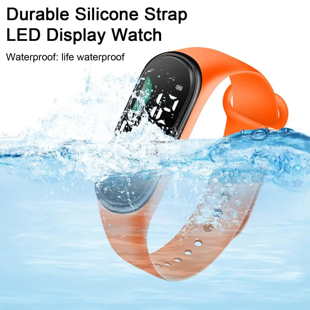 Reloj electrónico con correa de silicona naranja, pantalla digital negra de letra grande, diseñado como reloj deportivo digital impermeable.