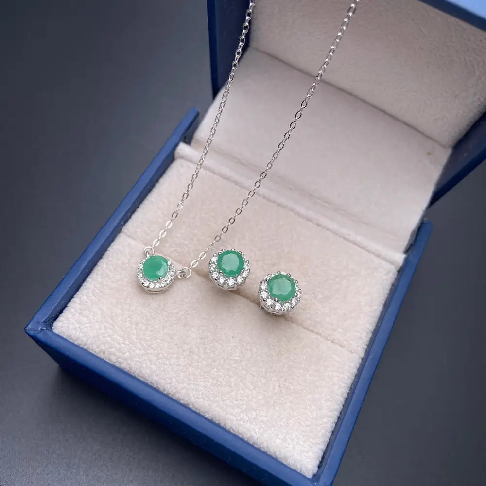 A delicate emerald sterling silver jewelry set featuring a necklace and matching earrings with vibrant green jade stones surrounded by sparkling diamond halos.
