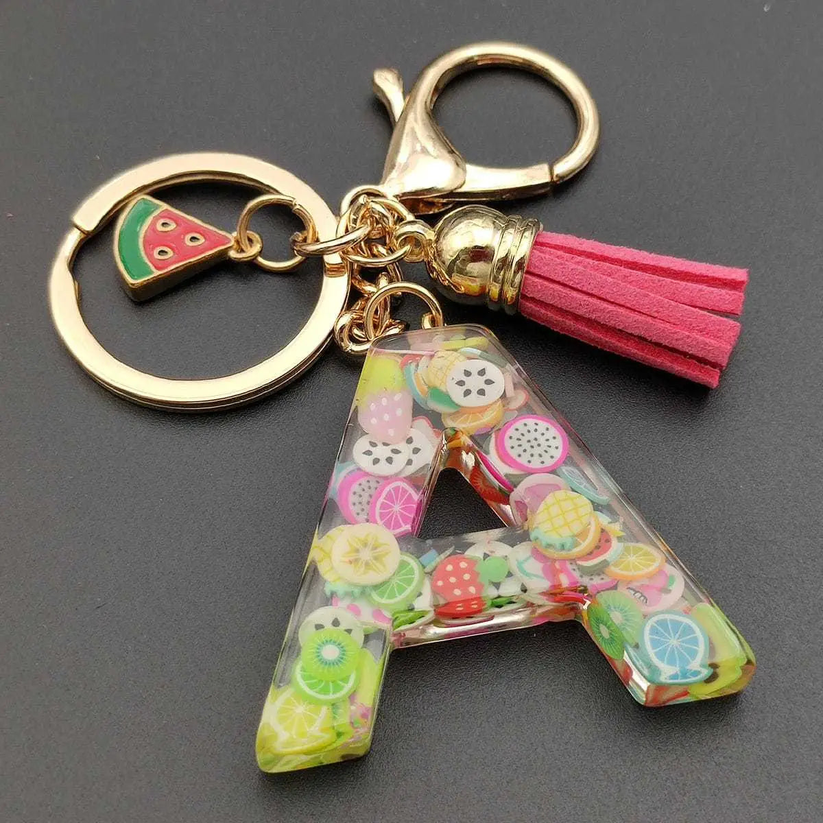 Clear resin letter a keychain filled with colorful fruit slices, featuring a gold-tone clasp, pink tassel, and watermelon charm in the fruit letter resin keychain initial alphabet key ring collection.