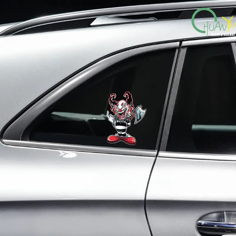 Un autocollant de voiture de clown maléfique rouge et noir vibrant représentant un clown de dessin animé à la grimace menaçante tenant une hache sur un autocollant imperméable pour vitres de voiture.