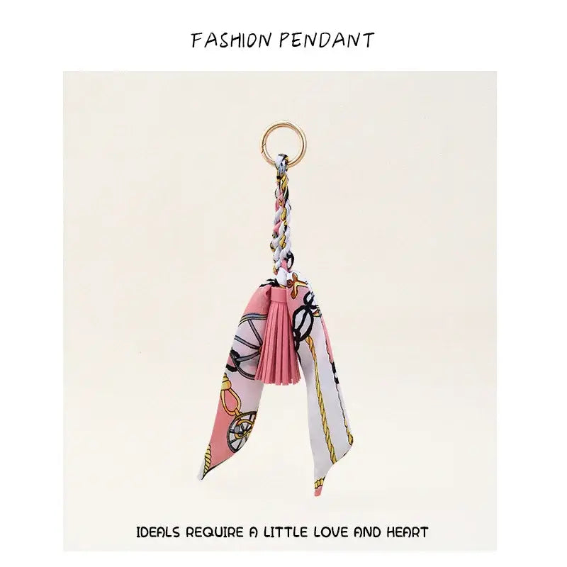 Porte-clés à gland de foulard en soie pour sacs, avec un foulard en soie rose et blanc à motif, un anneau à finition dorée et un gland décoratif.