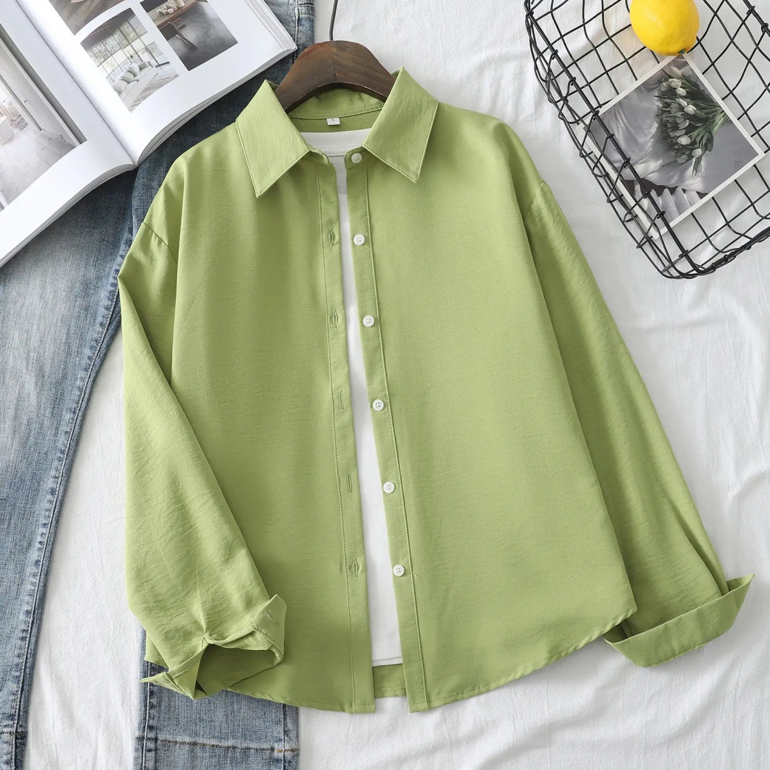 Eine hellgrüne Damen-Casualbluse aus Baumwollmischgewebe mit langen Ärmeln mit klassischem Kragen und weißen Knöpfen.