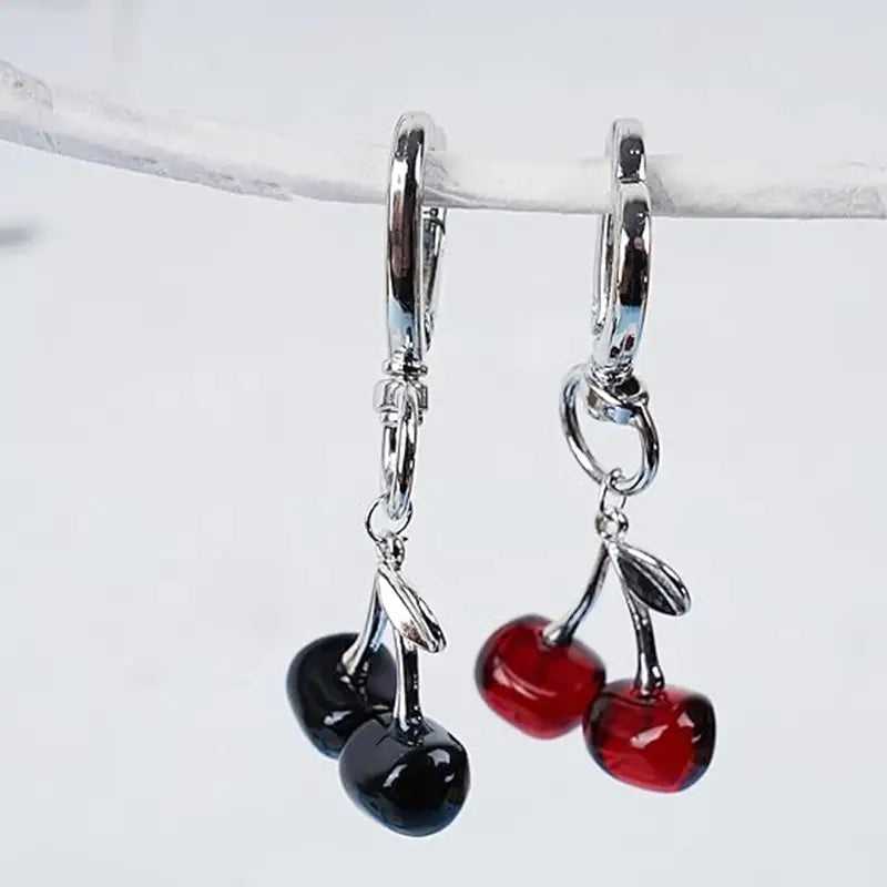 a pair of silver-toned hoop earrings featuring dangling cherry charms in glossy red and black glass designed as a cherry bag charm heart keychain accessory
