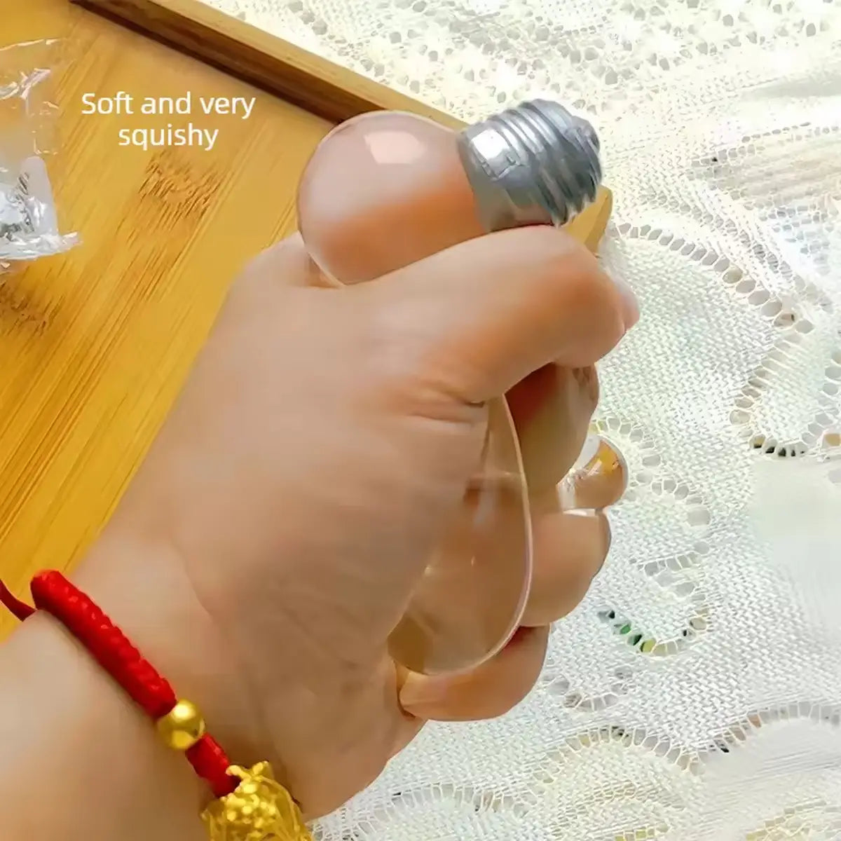 Light bulb squeeze toy sensory stress reliever made of transparent squishy material with a metallic screw-top base.
