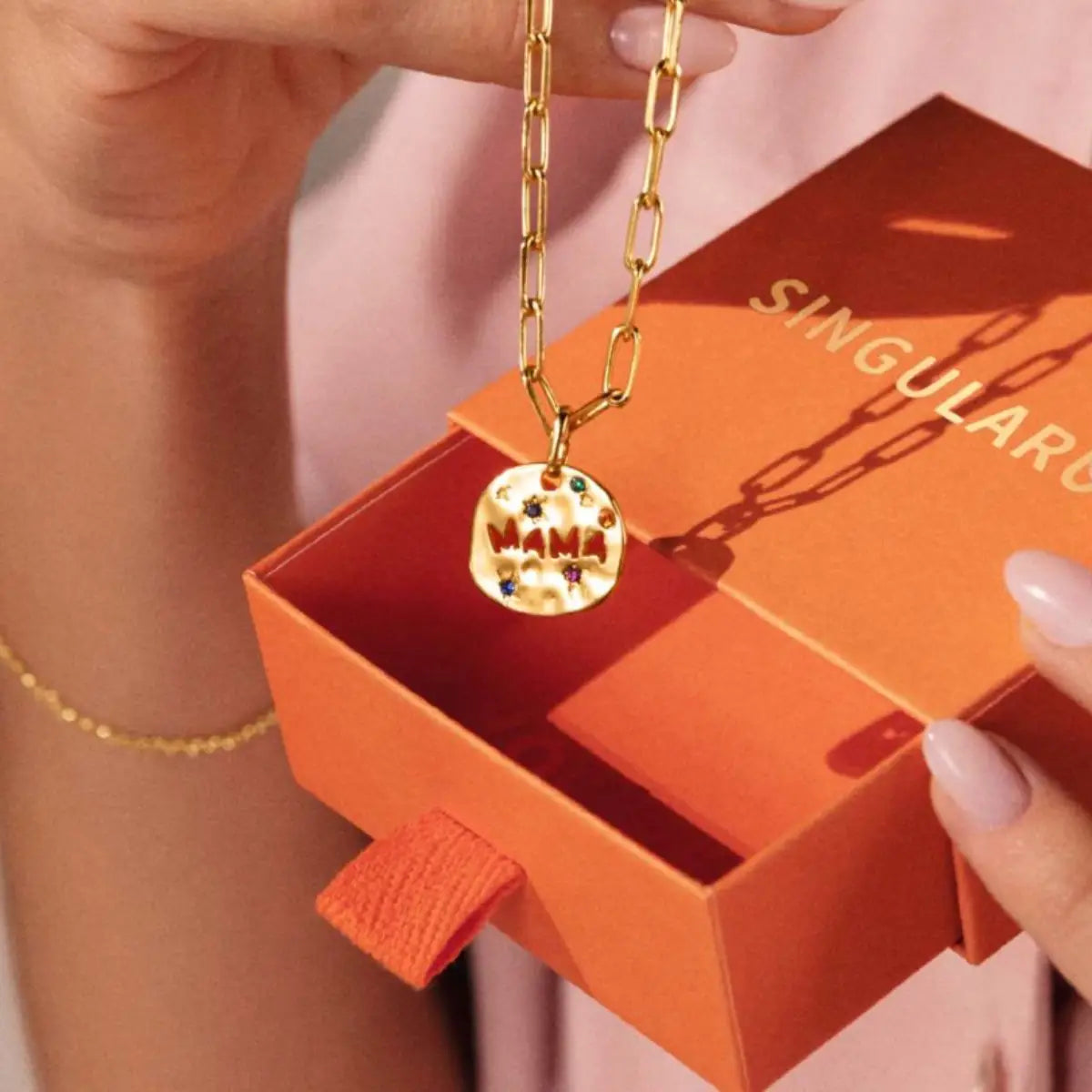Collier en chaîne dorée avec pendentif rond en acier inoxydable à texture, gravé « Mama » et orné de pierres précieuses colorées.