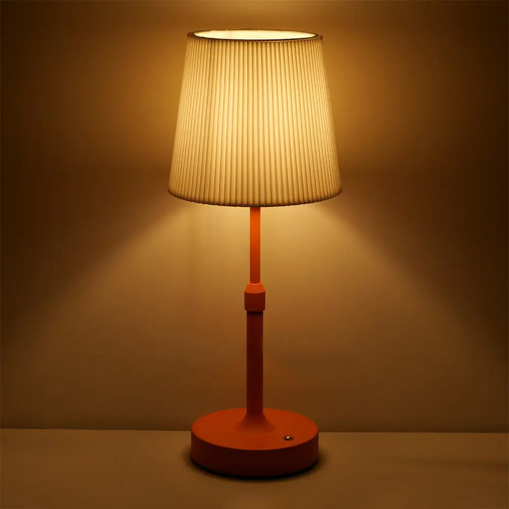 Warmtonige orangefarbene Touch-Tischlampe mit einem plissierten cremefarbenen Stoffschirm, von vorn dargestellt.