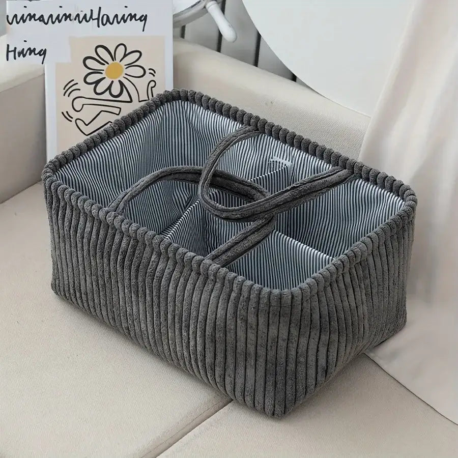 Grauer Cordstoff-Boho-Aufbewahrungskorb mit gestreiftem Innenfutter und geflochtenen Griffen, ausgelegt als Organizer mit mehreren Fächern.