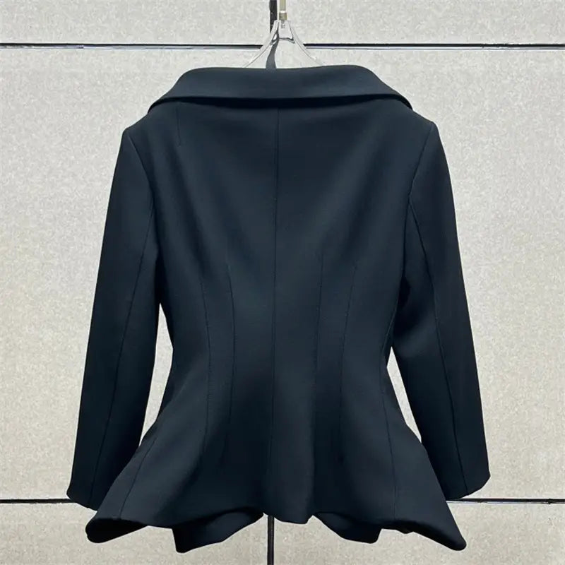 Blazer ceinture à volants noirs avec un col structuré et des manches longues, associé à une jupe crayon grise taille haute de longueur genou au style Y2K.