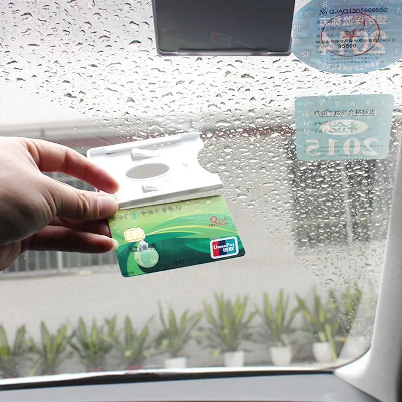 Tarjeta de crédito verde con chip plateado y logotipo de UnionPay, mostrada junto con un soporte para tarjeta en el parabrisas verde diseñado para multas de estacionamiento.