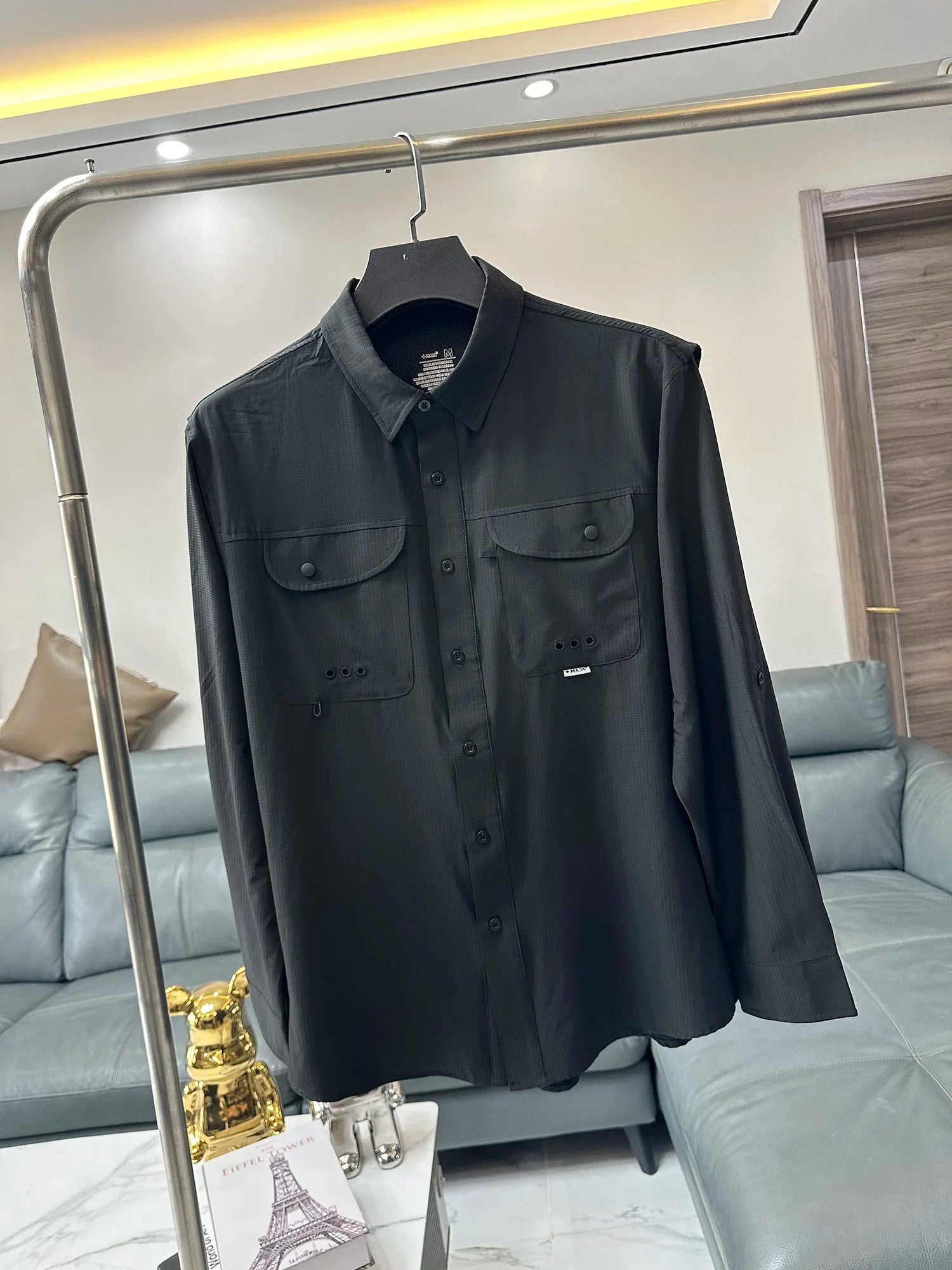 Men’s tactical outdoor long sleeve shirt in black featuring two chest pockets and a subtle brand tag on the left pocket.