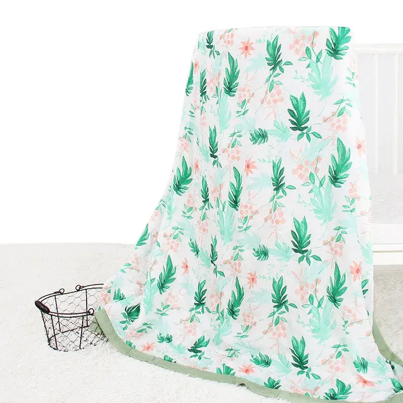 Aus weicher, leichter Musselin gefertigter Bambus-Baumwoll-Floral-Swaddle für Babys mit einem zarten botanischen Muster aus minzgrünen Blättern und blassrosa Blumen auf weißem Hintergrund