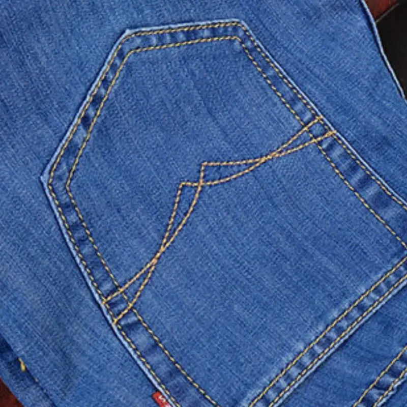 Jeans stretch en denim à jambe droite pour homme en bleu, avec une poche arrière présentant une couture jaune et une petite étiquette rouge en bas.