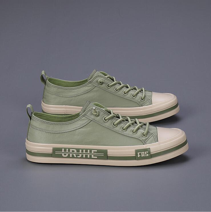 Baskets décontractées en toile pour hommes vert menthe, avec des coques en caoutchouc blanc et des semelles, présentant une discrète bande vert olive le long de la semelle intermédiaire conçue comme des chaussures d’été légères.